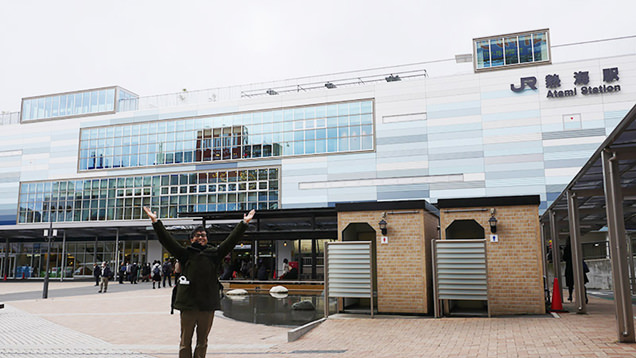 熱海駅前で両手を上げて到着を喜ぶライター地主恵亮