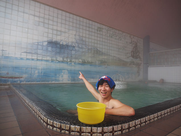 出町温泉の富士山の背景画を前に入浴する毎川直也