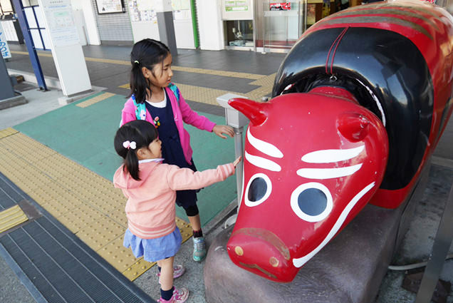 巨大な赤べこに触る姉妹