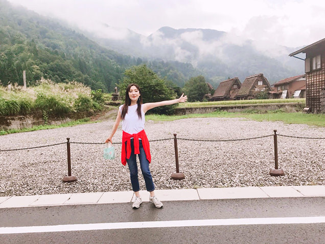 白川郷をバックに立つライター川崎